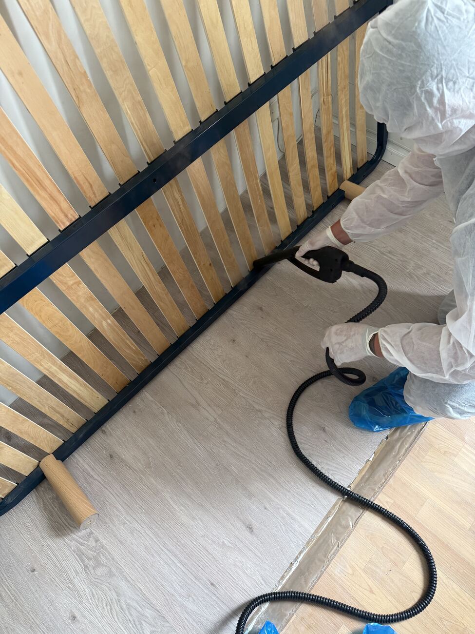 Traitement des punaises de lit à la vapeur sèche sur un sommier à lattes démonté, réalisé par un technicien AM-PureZone en combinaison à Saint-Nazaire